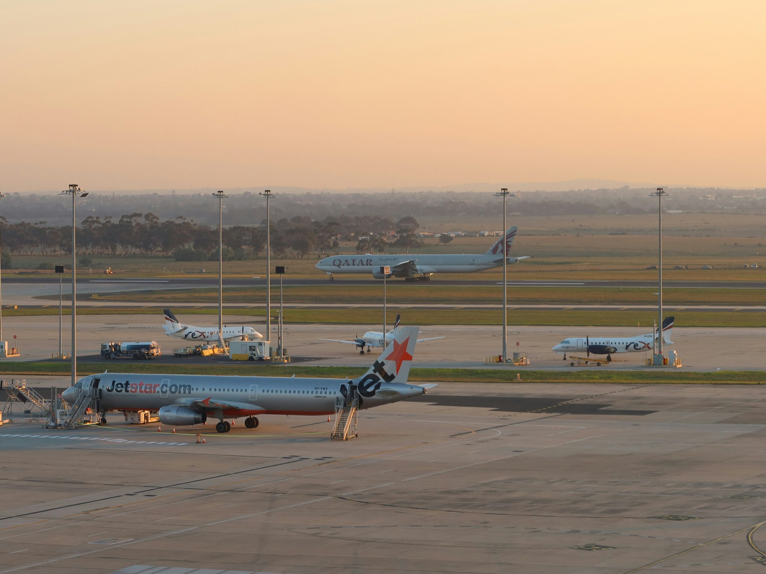 Commercial aircraft parked on airport tarmac at sunset during summer 2026 aviation peak season